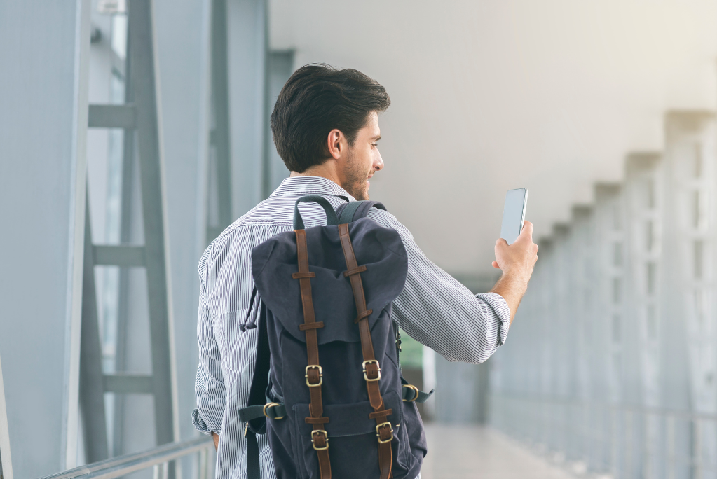 Пътуващ мъж използва телефон на летище
